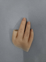A custom-crafted, three-finger silicone prosthesis resting on a grey surface. The piece features a wide, tapered base designed for partial hand amputations, complete with highly realistic skin textures, knuckles, and fingernails.