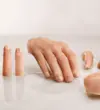 A diverse collection of hyper-realistic custom silicone prostheses, including individual fingers, a partial hand, a nose, an ear, and a facial piece, displayed on a clean, bright surface.